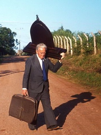 A man carrying the Pilgrim Mother shrine along a country road