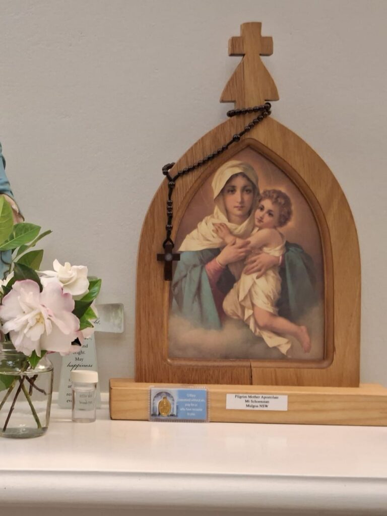 The Pilgrim Mother shrine set up in a home beside flowers